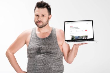 kilolu adam kamera bakıyor ve beyaz izole ekranda airbnb web sitesi ile dizüstü bilgisayar tutarak
