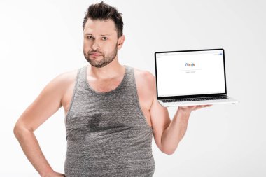 kilolu adam kamera bakıyor ve beyaz izole ekranda google web sitesi ile dizüstü bilgisayar tutarak