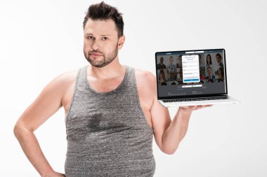 kilolu adam kamera bakıyor ve beyaz izole ekranda linkedin web sitesi ile dizüstü bilgisayar tutarak