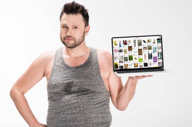 kilolu adam kamera bakıyor ve beyaz izole ekranda pinterest web sitesi ile dizüstü bilgisayar tutarak