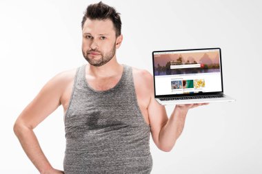 kilolu adam kamera bakıyor ve ekranda beyaz izole shutterstock web sitesi ile dizüstü bilgisayar tutarak