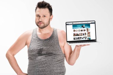 kilolu adam kamera bakıyor ve beyaz izole ekranda amazon web sitesi ile dizüstü bilgisayar tutarak