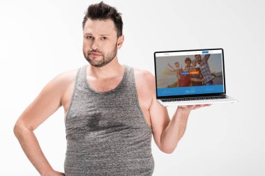 kilolu adam kamera bakıyor ve beyaz izole ekranda couchsurfing web sitesi ile dizüstü bilgisayar tutarak