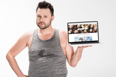kilolu adam kamera bakıyor ve beyaz izole ekranda depositphotos web sitesi ile dizüstü bilgisayar tutarak