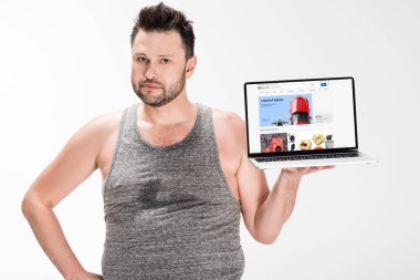 kilolu adam kamera bakıyor ve beyaz izole ekranda ebay web sitesi ile dizüstü bilgisayar tutarak