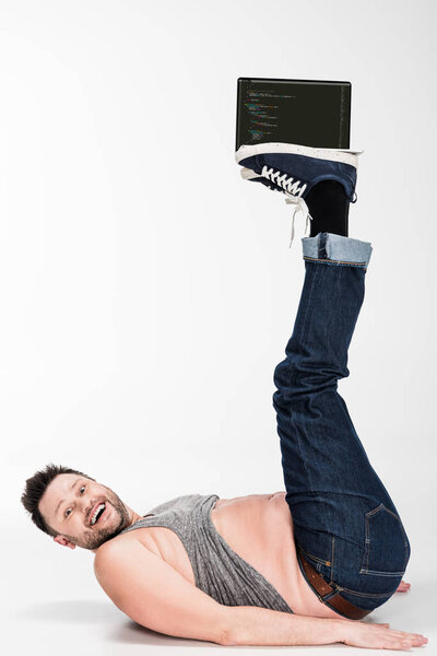 excited overweight man looking at camera and holding with legs laptop with microsoft windows on screen 