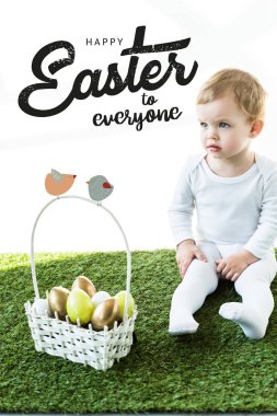 child sitting on green grass near basket with Easter eggs and happy Easter to everyone lettering above clipart