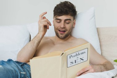 seks kitabında sorunları okurken fikir işareti gösteren yakışıklı gömleksiz adam seçici odak