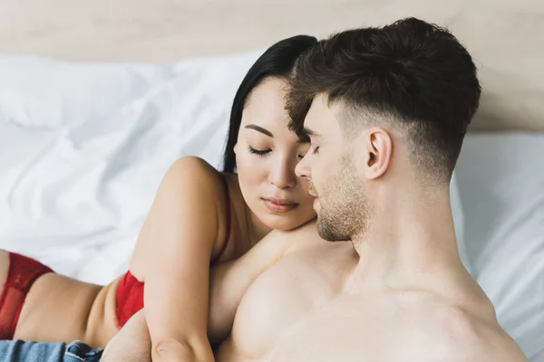 Beautiful Asian Woman Red Lingerie Hugging Shirtless Boyfriend While Lying — Stock Photo, Image