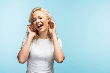 kapalı gözlü neşeli kadın kulaklıkla müzik dinliyor ve mavi şarkı söylüyor 