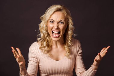 emotional blonde woman gesturing and screaming isolated on black  clipart