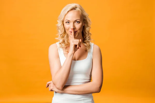 Cheerful Blonde Woman Looking Camera Showing Hush Sign Isolated Orange — Stock Photo, Image