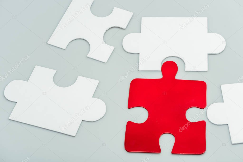 red and white jigsaw pieces isolated on grey 