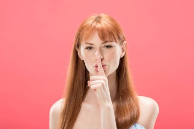 kameraya bakan ve pembe izole gizli jest gösteren redhead kız ön görünümü