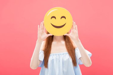 Kiev, Ukrayna-Mayıs 23, 2019: Kızıl saçlı kız ön görünümü pembe üzerinde izole Smiley tutan