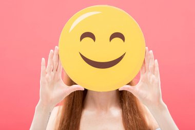 Kiev, Ukrayna-Mayıs 23, 2019: Kızıl saçlı kız ön görünümü pembe üzerinde izole Smiley tutan