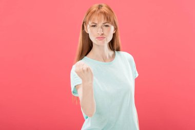 t-shirt yumruk gösteren ve pembe izole kamera bakarak hoşnutsuz redhead kadın ön görünümü