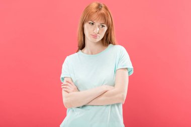 t-shirt çapraz kolları ile ayakta ve uzak pembe izole bakarak dalgın kızıl saçlı genç kadının ön görünümü