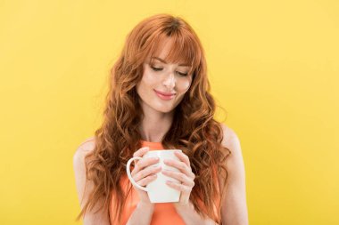 gülümseyen kızıl saçlı kız sarı izole kahve fincan tutan