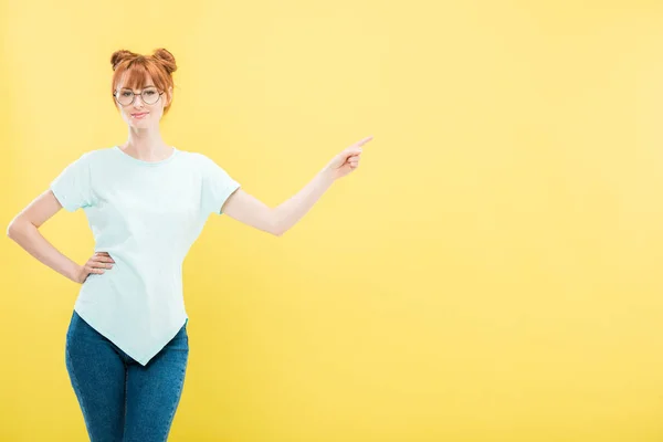 Smiling Redhead Girl Glasses Standing Hand Hip Pointing Finger Isolated — Stock Photo, Image