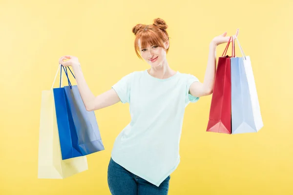 Smiling Redhead Girl Holding Shopping Bags Looking Camera Isolated Yellow — Stock Photo, Image