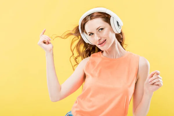 ヘッドフォンで音楽を聴き 黄色に孤立した笑顔の魅力的な赤毛の女性 — ストック写真