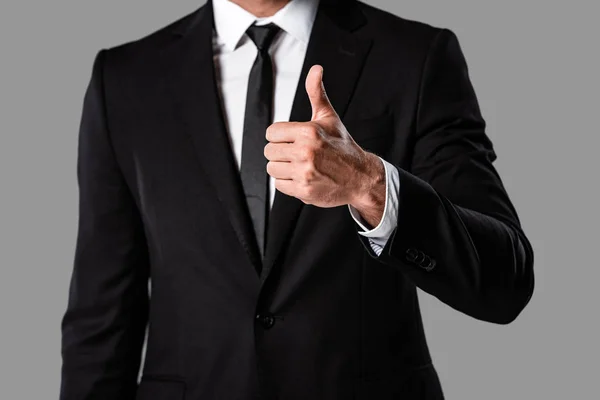 部分视图的商人在黑色西装显示竖起大拇指隔离在灰色 — 图库照片