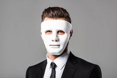 mysterious businessman in black suit and white mask isolated on grey clipart