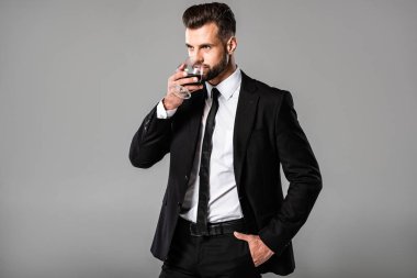 siyah takım elbiseli yakışıklı işadamı gri izole viski içme
