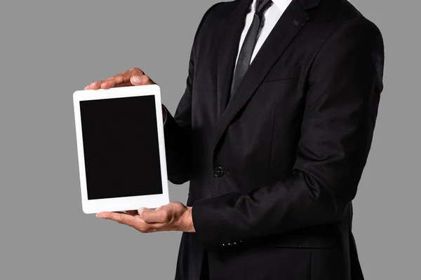 裁剪视图的商人在黑色西装显示数字平板电脑与空白屏幕隔离在灰色 — 图库照片