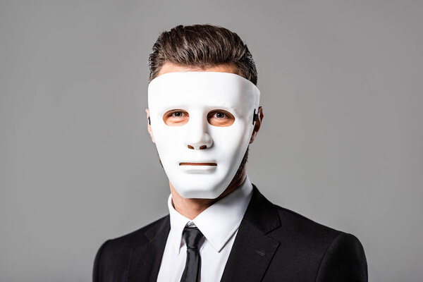 mysterious businessman in black suit and white mask isolated on grey