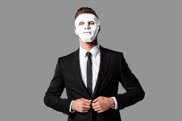 confident handsome businessman in black suit and white mask isolated on grey