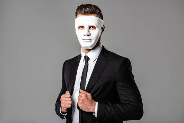 businessman in black suit and white mask isolated on grey