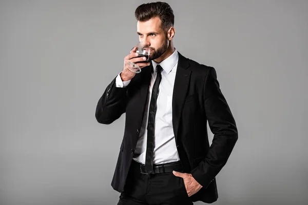 Schöner Geschäftsmann Schwarzen Anzug Trinkt Whisky Isoliert Auf Grau — Stockfoto