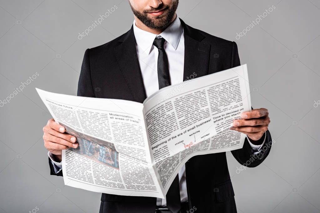 cropped view of businessman in black suit with newspaper isolated on grey