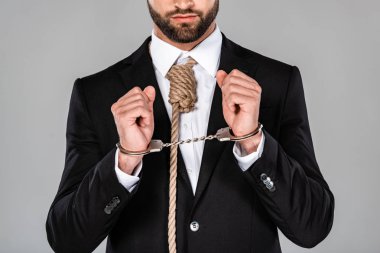 cropped view of businessman in black suit and handcuffs with noose on neck isolated on grey clipart