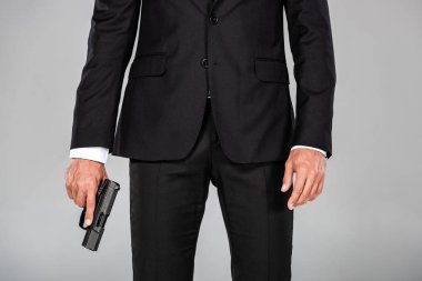gri izole silah ile siyah takım elbiseli ajanın kısmi görünümü