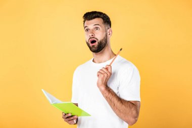 sarı izole kalem ve defter tutan açık ağız ile beyaz t-shirt şok yakışıklı adam