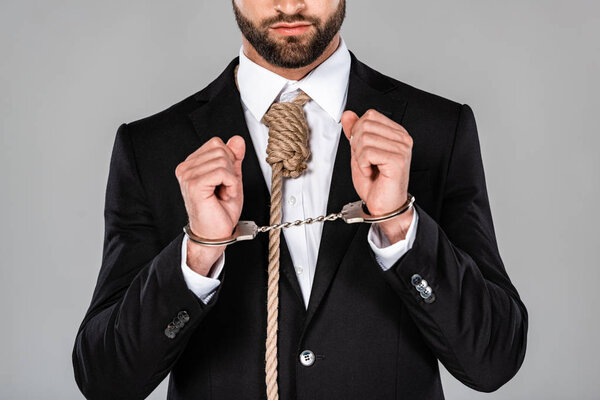 cropped view of businessman in black suit and handcuffs with noose on neck isolated on grey