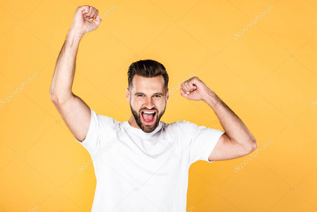 happy handsome man in white t-shirt showing yes gesture isolated on yellow