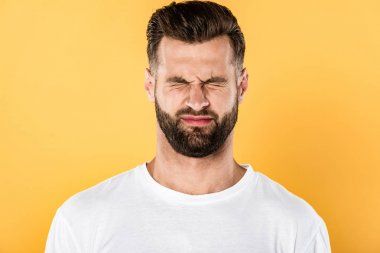scared handsome man in white t-shirt squinting isolated on yellow clipart