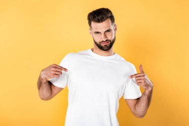 egoist yakışıklı adam beyaz t-shirt kendini sarı izole parmakları ile işaret