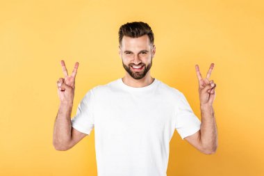 beyaz t-shirt mutlu yakışıklı adam kameraya bakarak ve sarı izole barış işaretleri gösteren