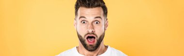 panoramic shot of shocked handsome man in white t-shirt with open mouth isolated on yellow clipart