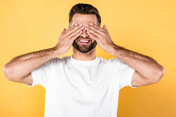 Lycklig Snygg Man Vit Shirt Med Händerna Ögonen Isolerade Gult — Stockfoto