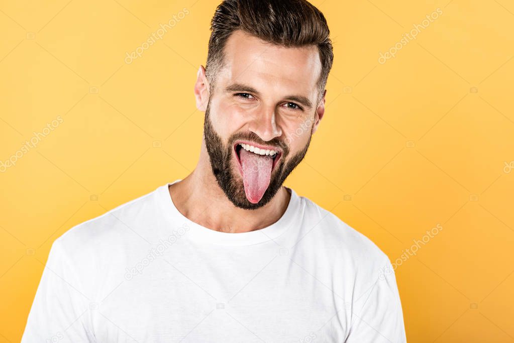 handsome funny man in white t-shirt showing tongue isolated on yellow