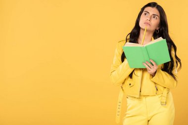 kalem ve kitap tutan pensive kız, sarı izole 