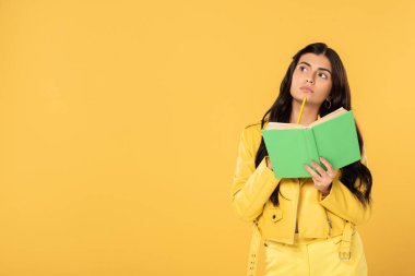düşünceli öğrenci kalem ve kitap tutan, sarı izole 