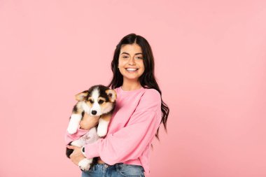 galli Corgi köpek yavrusu tutan gülümseyen kadın, pembe izole