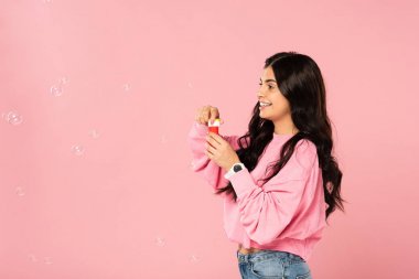 pembe izole sabun kabarcıkları üfleme gülümseyen kız